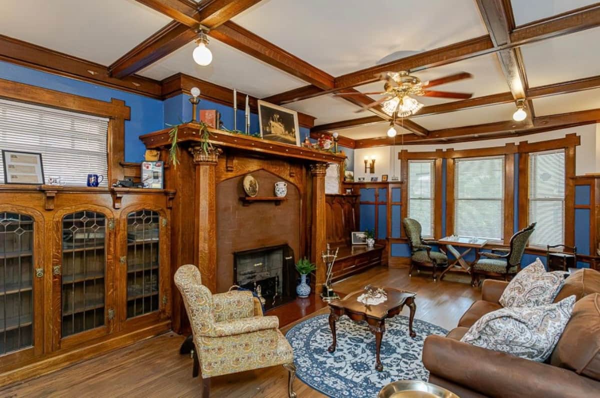 Living room with original woodwork, fireplace and green seating
