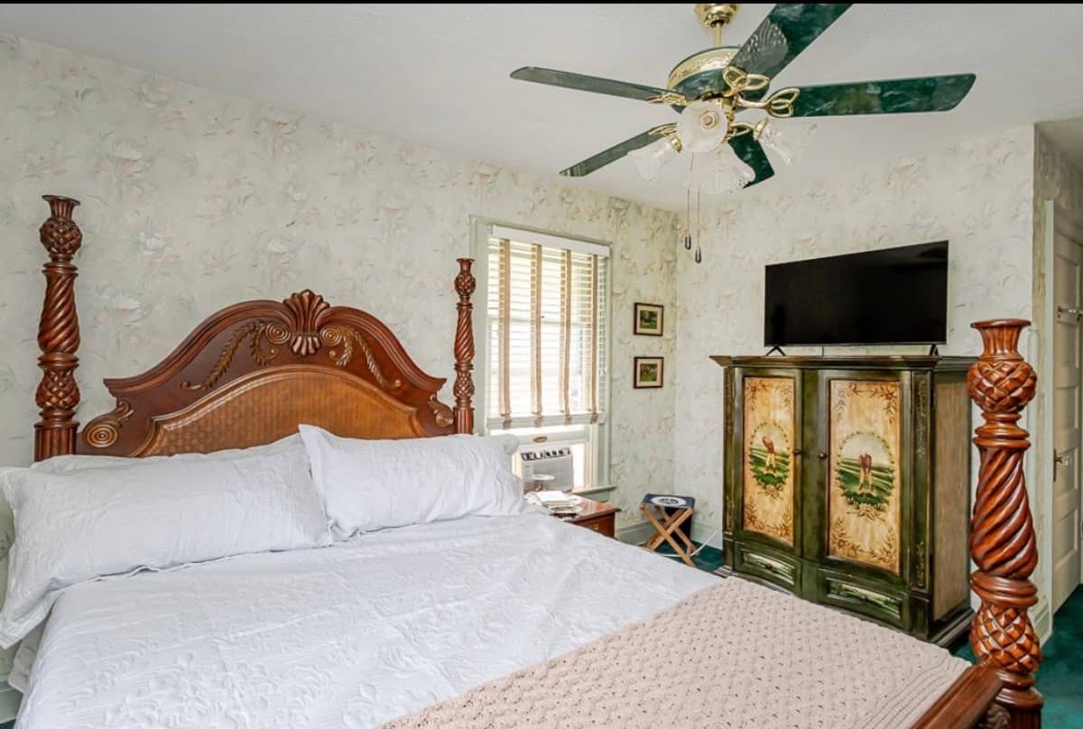 Bedroom with an ornate carved wood bed, television and painted storage cabinet