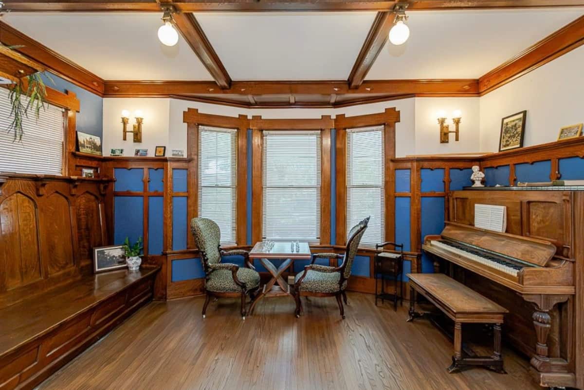Spacious living room with piano and original wooden trim